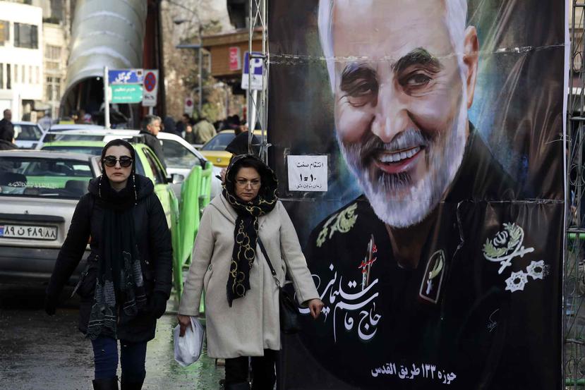 Mujeres caminan junto a un cartel con la imagen del general de la Guardia Revolucionaria Qassem Soleimani. (AP)