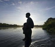 Un hombre carga a su hija al cruzar el río Bravo de Ciudad Acuña, México, a Del Río, Texas.