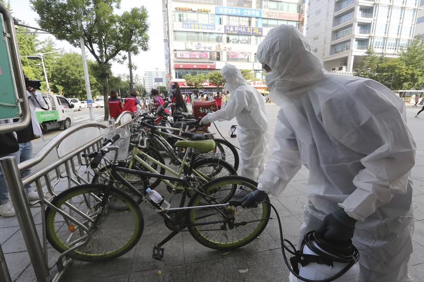 Trabajadores y voluntarios desinfectan áreas comunes en Corea del Sur para contener la propagación de COVID-19.