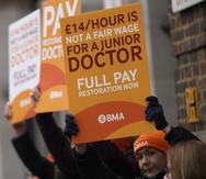 Médicos de inicio de carrera muestran pancartas mientras realizan un paro de labores afuera del Hospital Santa María, en Londres, el martes 14 de marzo de 2023.