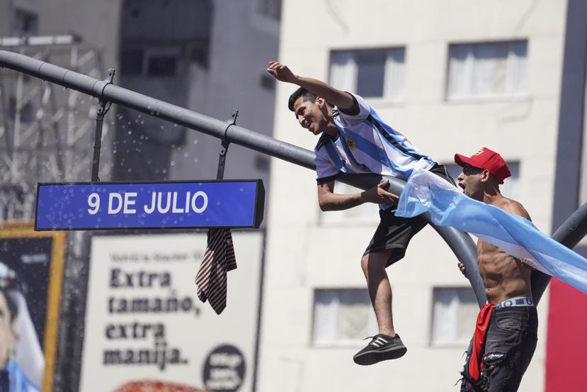 Fanáticos argentinos se subieron a un poste en Buenos Aires durante los festejos por la coronación en la Copa del Mundo.