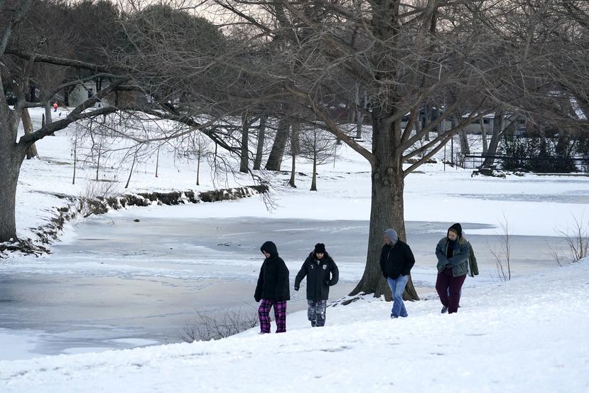 La gente camina a lo largo del borde mirando el lago congelado en Cottonwood Park en Richardson, Texas.