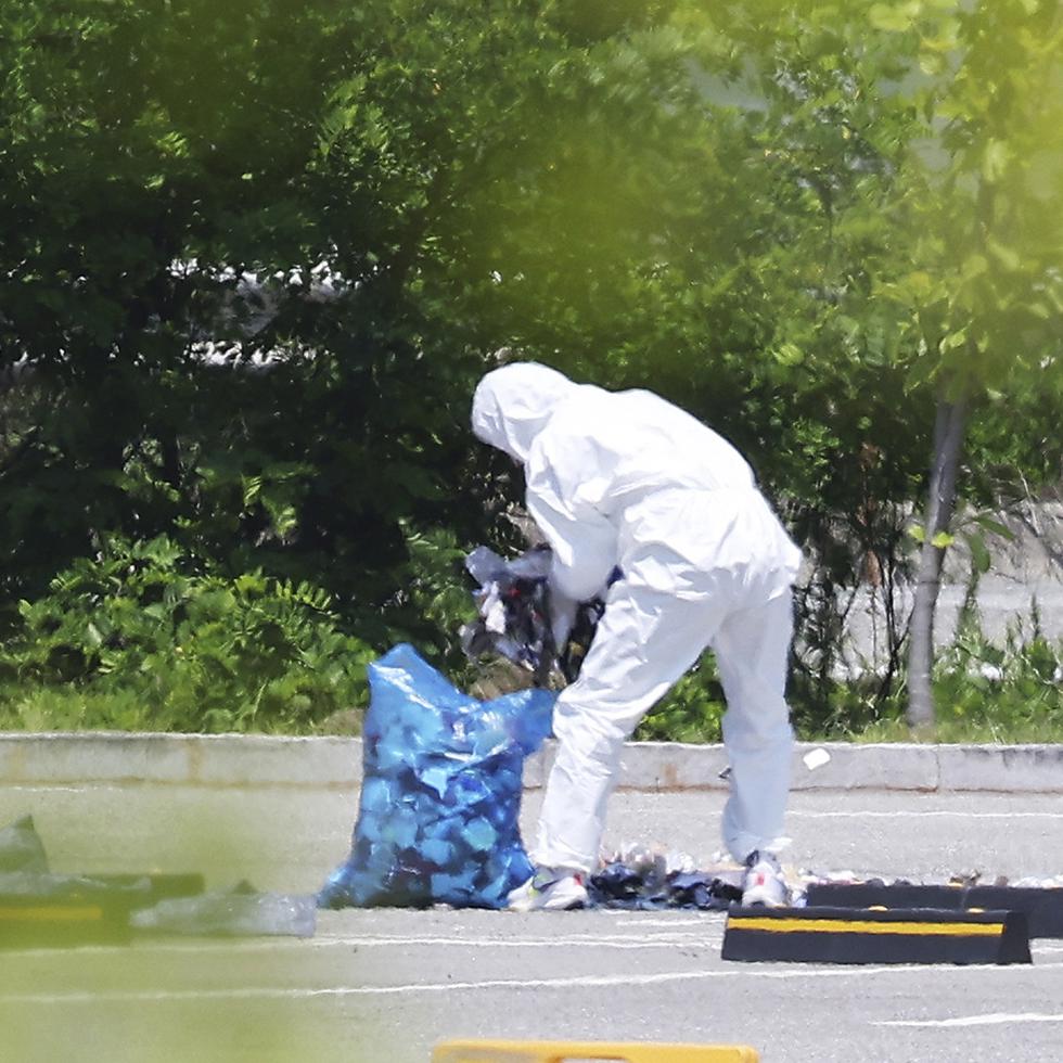 Un funcionario con material de protección recoge basura de un globo probablemente enviado por Corea del Norte en Siheung, Corea del Sur, el domingo 2 de junio de 2024.