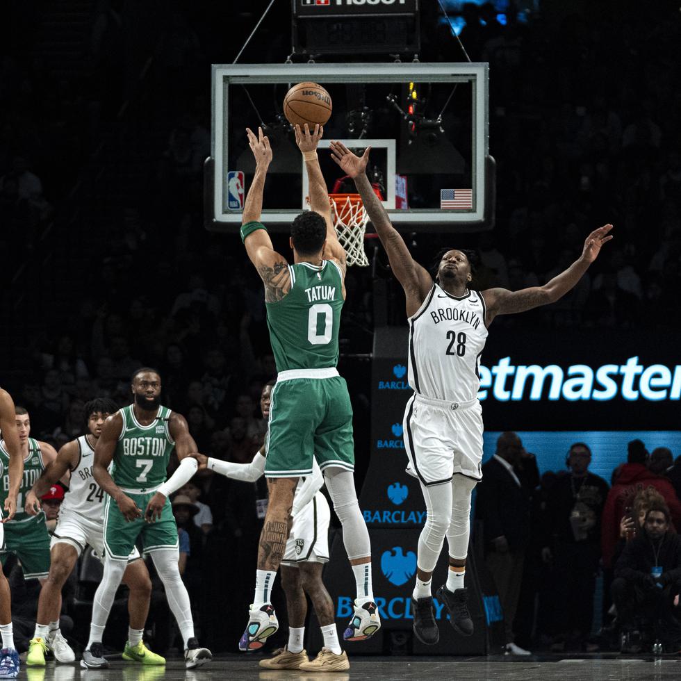 El alero de los Celtics de Boston Jayson Tatum (0) lanza ante el alero de los Nets de Brooklyn Dorian Finney-Smith (28) durante la primera mitad del juego del martes.