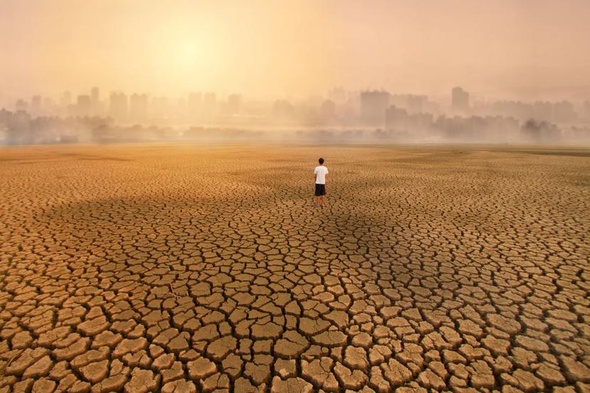 Un hombre de pie en una tierra vacía y seca, mirando a la gran ciudad. (Shutterstock)