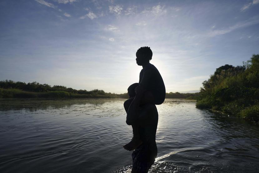 Un hombre carga a su hija al cruzar el río Bravo de Ciudad Acuña, México, a Del Río, Texas.