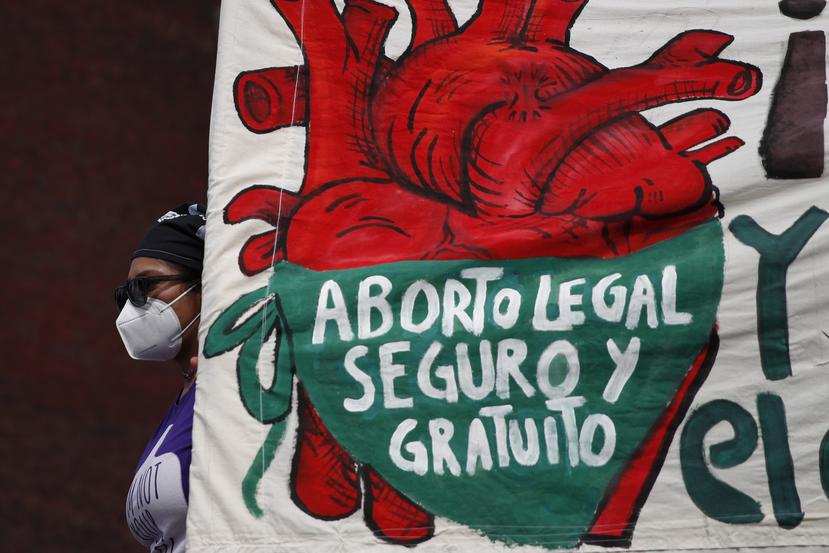 Una mujer sostiene una pancarta que dice en español "Aborto legal, seguro y gratuito" mientras manifestantes por el derecho al aborto se manifiestan frente al Congreso Nacional.