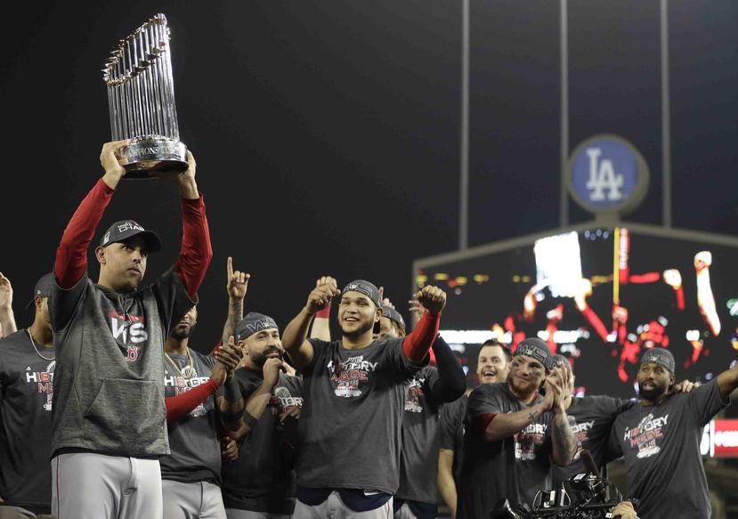 El dirigente cagueño Alex Cora alza el trofeo de campeonato de la Serie Mundial luego que los Medias Rojas eliminaron a los Dodgers de Los Ángeles.  (AP / Jae C. Hong)
