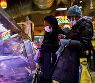 En esta imagen del 16 de febrero de 2022, clientes portan mascarillas para protegerse de la propagación del coronavirus mientras realizan sus compras en el Reading Terminal Market, en Filadelfia.