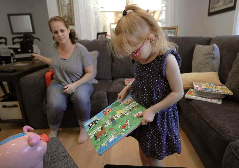 En fotografía del lunes 23 de julio de 2018, Brooke Adams, de cinco años, juega con sus juguetes frente a su madre Jana momentos antes de sufrir un ataque de epilepsia en su hogar en Santa Rosa, California.