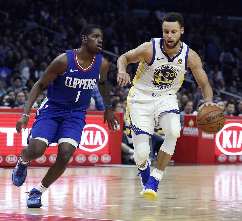 Stephen Curry, alero de los Warriors de Golden State, dribla a Jawun Evans, de los Clippers de Los Ángeles, en el partido disputado el sábado 6 de enero de 2018. (AP /Alex Gallardo)