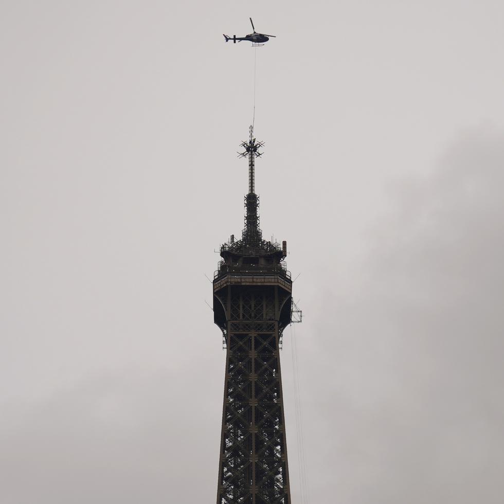 Un helicóptero Eurocopter Ecureuil 2 instala una nueva antena TDF (TeleDiffusion de France) de transmisión de telecomunicaciones en la parte superior de la Torre Eiffel, en París, el martes 15 de marzo de 2022.