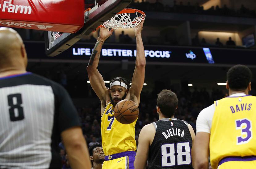 El jugador de los Lakers de Los Ángeles JaVale McGee cuelga del aro tras una clavada ante el jugador de los Kings de Sacramento Nemanja Bjelica. (AP)