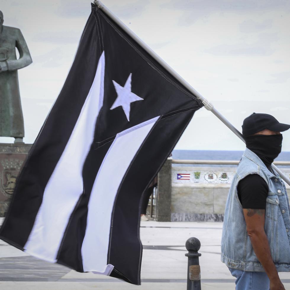 Un manifestante carga la bandera de "luto" de Puerto Rico.