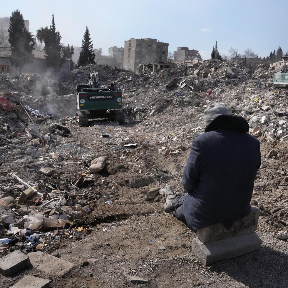 Un hombre observa cómo las excavadoras retiran los escombros de su edificio en la ciudad de Kahramanmaras, en el sur de Turquía, el miércoles 15 de febrero de 2023.