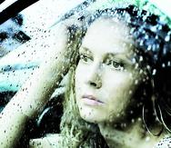 Sad young woman looking through window with a rain drops.
-----
