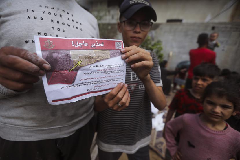 Palestinos sostienen folletos arrojados por aviones israelíes que les dicen que evacúen antes de una operación militar israelí en Rafah, en el sur de la Franja de Gaza.