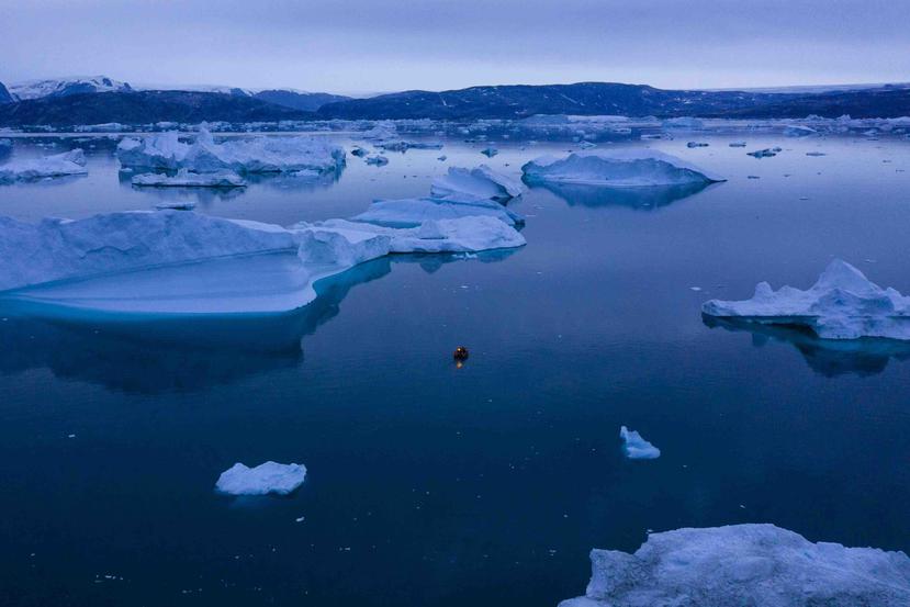 Un barco navega durante la noche entre unos icebergs en el este de Groenlandia. (AP)