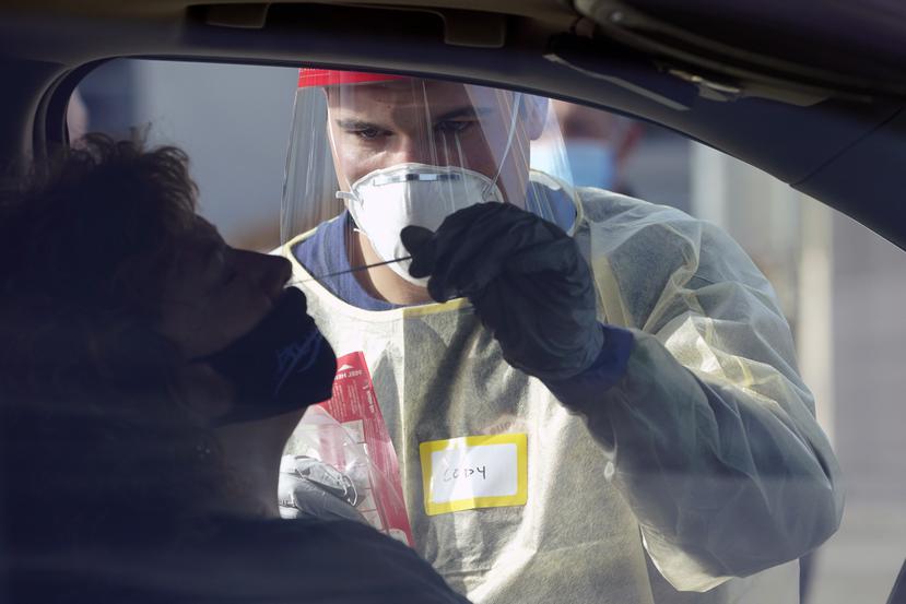 Un trabajador médico le toma la muestra nasal a una mujer para realizar la prueba molecular de COVID-19.