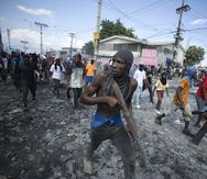 Un manifestante lleva un trozo de madera que simula un arma durante una protesta en la que se exigió la renuncia del primer ministro Ariel Henry en el área de Petion-Ville de Puerto Príncipe, Haití.