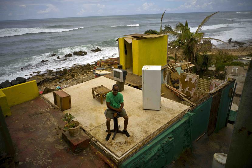 Roberto Figueroa Caballero está sentado sobre una mesa pequeña en su casa que quedó destruida tras el paso del huracán María. (AP / Ramón Espinosa)