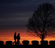 Una pareja camina por un parque en Kansas City, Missouri, a la puesta del sol.