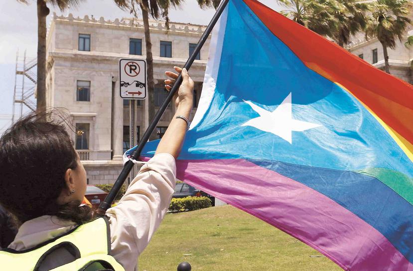 Una mujer ondea la bandera de Puerto Rico con los colores de la comunidad LGBTT. (Agencia EFE)