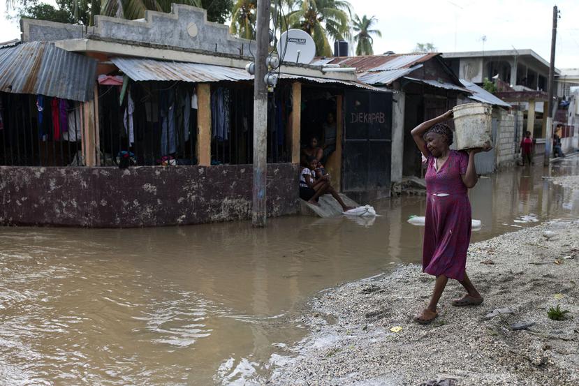 Una residente de Petit-Goaves, donde murieron 21 personas por el paso del ciclón, saca barro de su humilde residencia entre las calles que aún ayer parecían riachuelos por las lluvias del temporal.