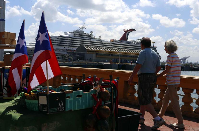 Dos turistas caminan frente a un crucero en el Puerto de San Juan. (GFR Media)