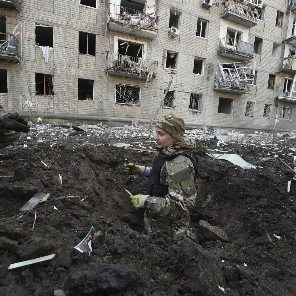 Policías inspeccionan un cráter frente a un edificio residencial dañado por un ataque ruso en Jarkív, Ucrania.