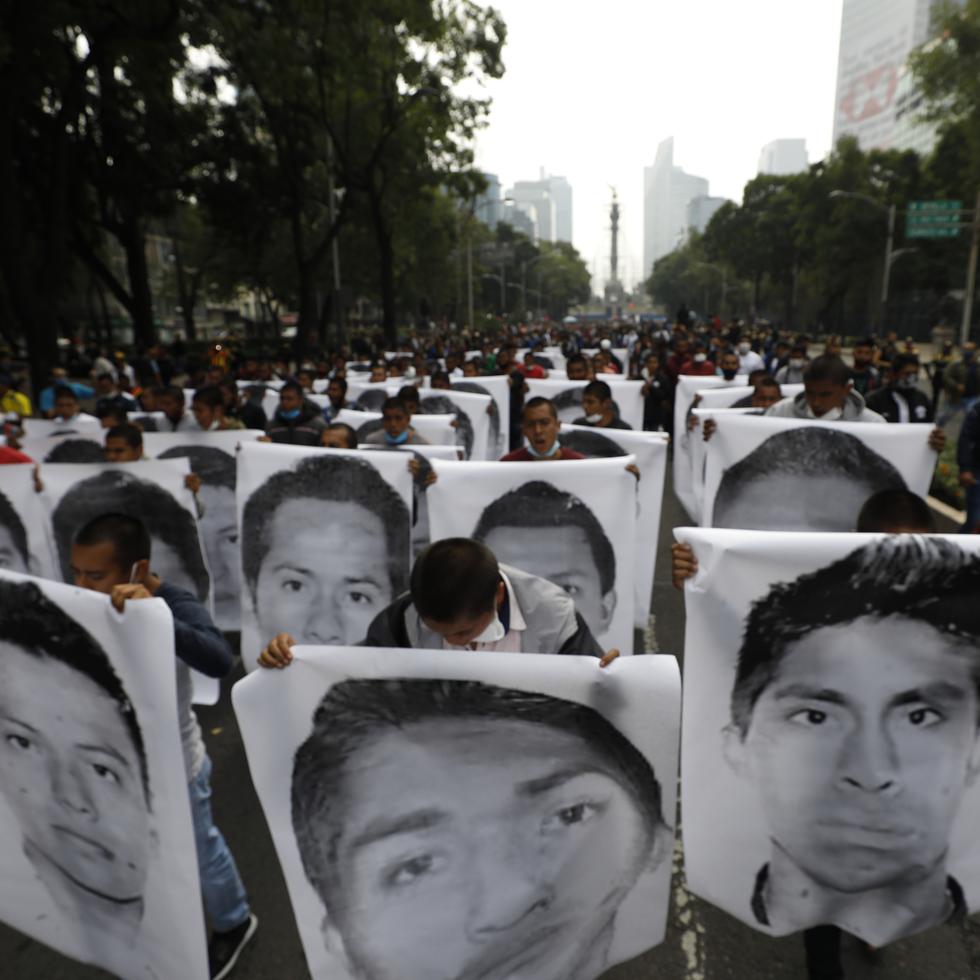 Estudiantes normalistas muestran las fotografías de los 43 estudiantes desaparecidos de la Escuela Normal Rural de Ayotzinapa al acompañar a los familiares en una marcha en 2020.