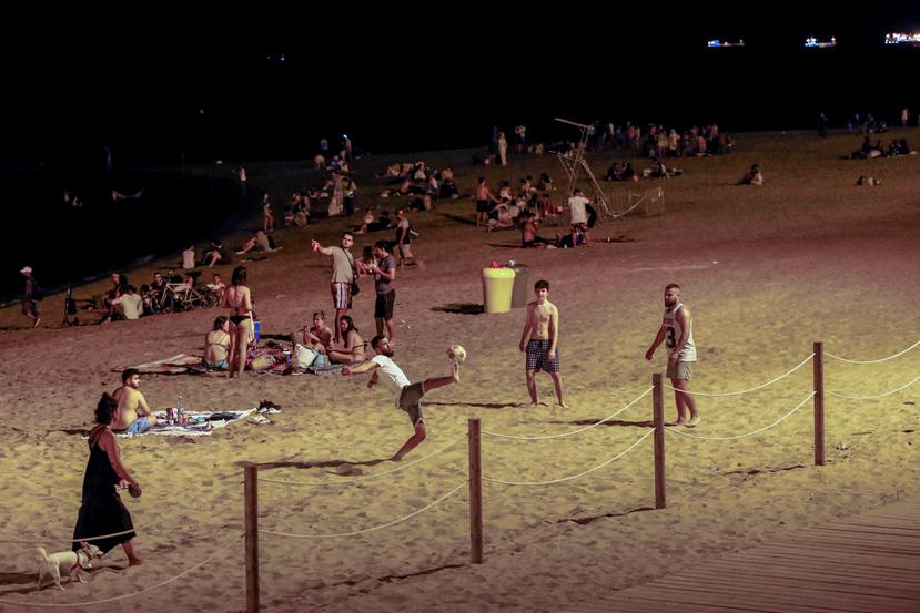 Varios jóvenes se divierten en una playa de Barcelona, anoche, tras el cierre de discotecas decretado por las autoridades.