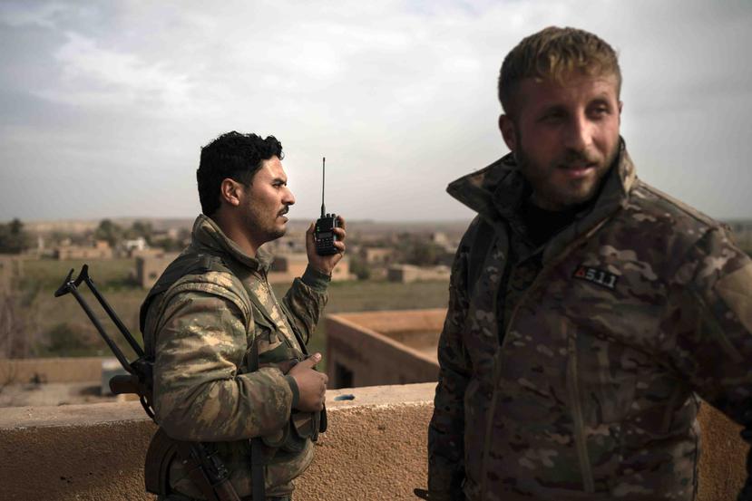 Unos soldados de las fuerzas democráticas sirias, con respaldo de Estados Unidos, se comunican por radio desde una posición elevada conforme continúa el combate contra miembros del grupo Estado Islámico en Baghouz, Siria. (AP /Felipe Dana)