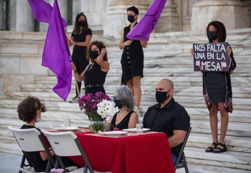 Sobre la mesa, que incluía una silla vacía, se colocaron margaritas color púrpura, representativas de la lucha feminista.