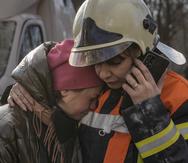 A firefighter comforts a woman outside a destroyed apartment building after a bombing in a residential area in Kyiv, Ukraine, Tuesday, March 15, 2022. Russia's offensive in Ukraine has edged closer to central Kyiv with a series of strikes hitting a residential neighborhood as the leaders of three European Union member countries planned a visit to Ukraine's embattled capital. (AP Photo/Vadim Ghirda)
