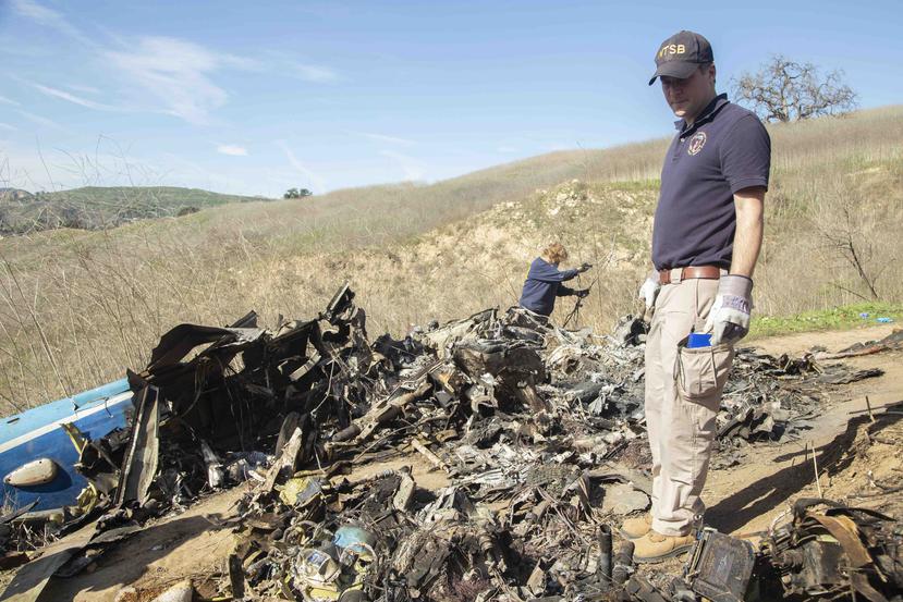Personal de la Junta Nacional de Seguridad en el Transporte examinan los restos del helicóptero estrellado. (AP)