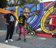 El entrenador Emilio "Millo" Lozada (izquierda) y el artista Don Rimx (derecha) posan ante el mural que muestra a Miguel Cotto y a Félix "Tito" Trinidad.