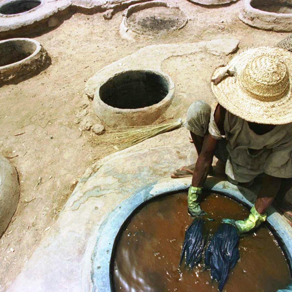 Sixty-year-old Malam Yakubu dyes cloth in a pit filled with indigo ink Thursday, March 26, 1998 in Kano, Nigeria where generations of his family have worked this trade for 500 years. Nigeria's economy is in the middle of a crisis crippling major mutinationals and small industries like Yakubu's family business whose sales have dropped because of the country's weakening currency. (AP Photo/David Guttenfelder) 