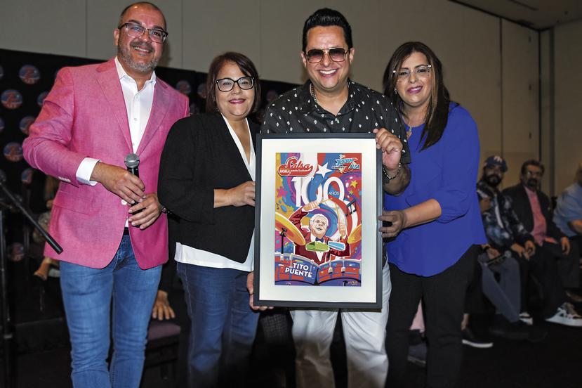 De izquierda a derecha, Marco Rodríguez "El Cacique", director de programación de Z93; Mildred Tirado, sub directora de Primera Hora;  Tito Puente Jr.; Ana Enid López, directora de Mercadeo de GFR Media, posan con el afiche conmemorativo creado por el artista Miguel Bayón.