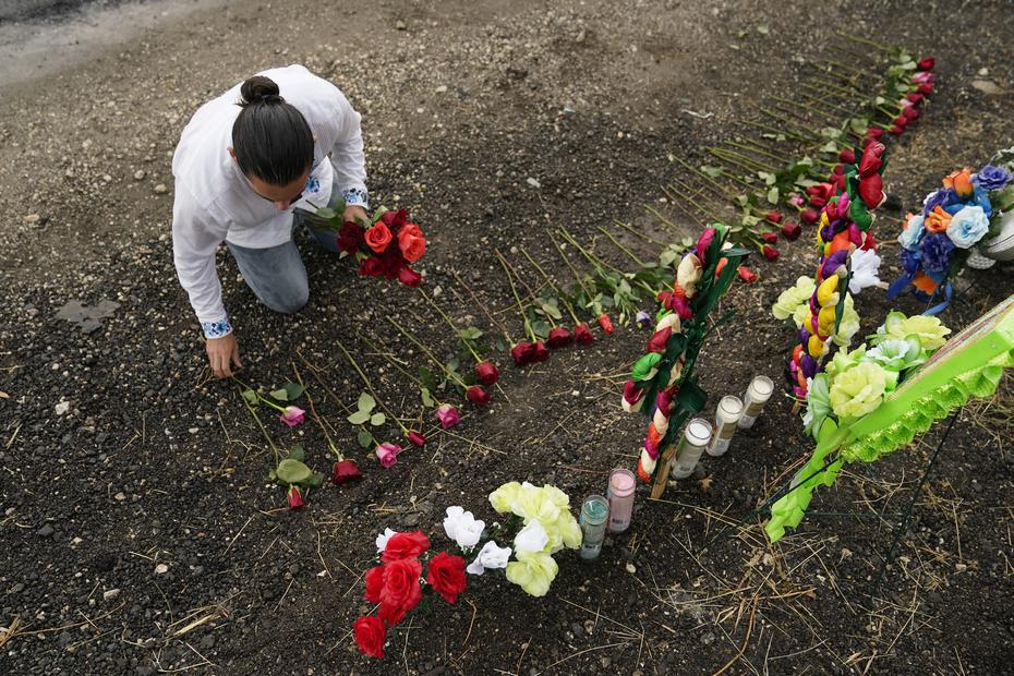 Un joven coloca rosas en un monumento improvisado en el sitio donde las autoridades encontraron a decenas de personas muertas en un semirremolque.