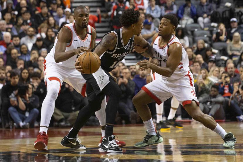 DeMar DeRozan, de los Spurs de San Antonio, conduce el balón entre Kyle Lowry (derecha) y Serge Ibaka, de los Raptors de Toronto, durante el partido del domingo. (Chris Young / The Canadian Press / AP)