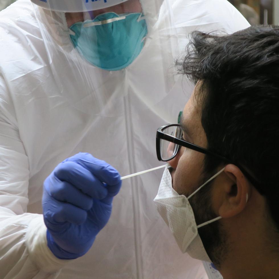 Un técnico de laboratorio inserta un hisopo en la nariz de un residente para la prueba del coronavirus en San Juan.