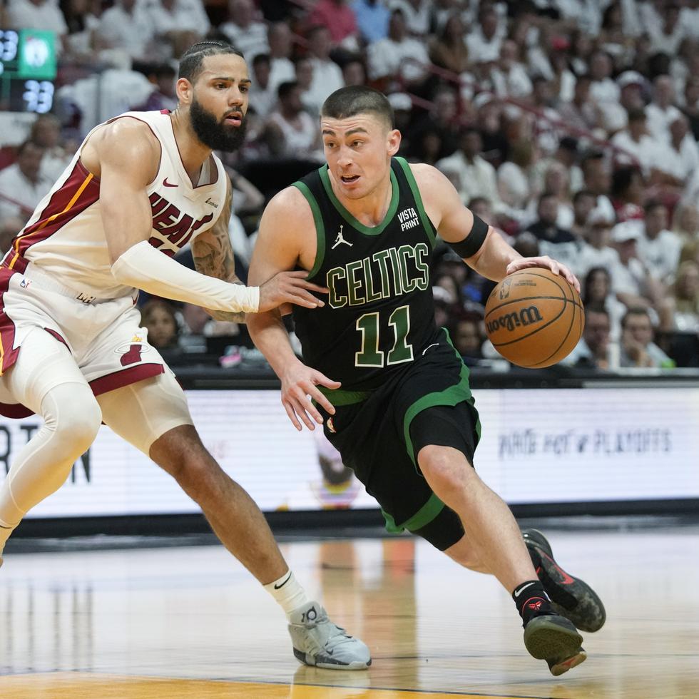 El base de los Celtics de Boston, Payton Pritchard, avanza con el balón hacia la canasta frente al alero del Heat de Miami, Caleb Martin, en el Juego tres.