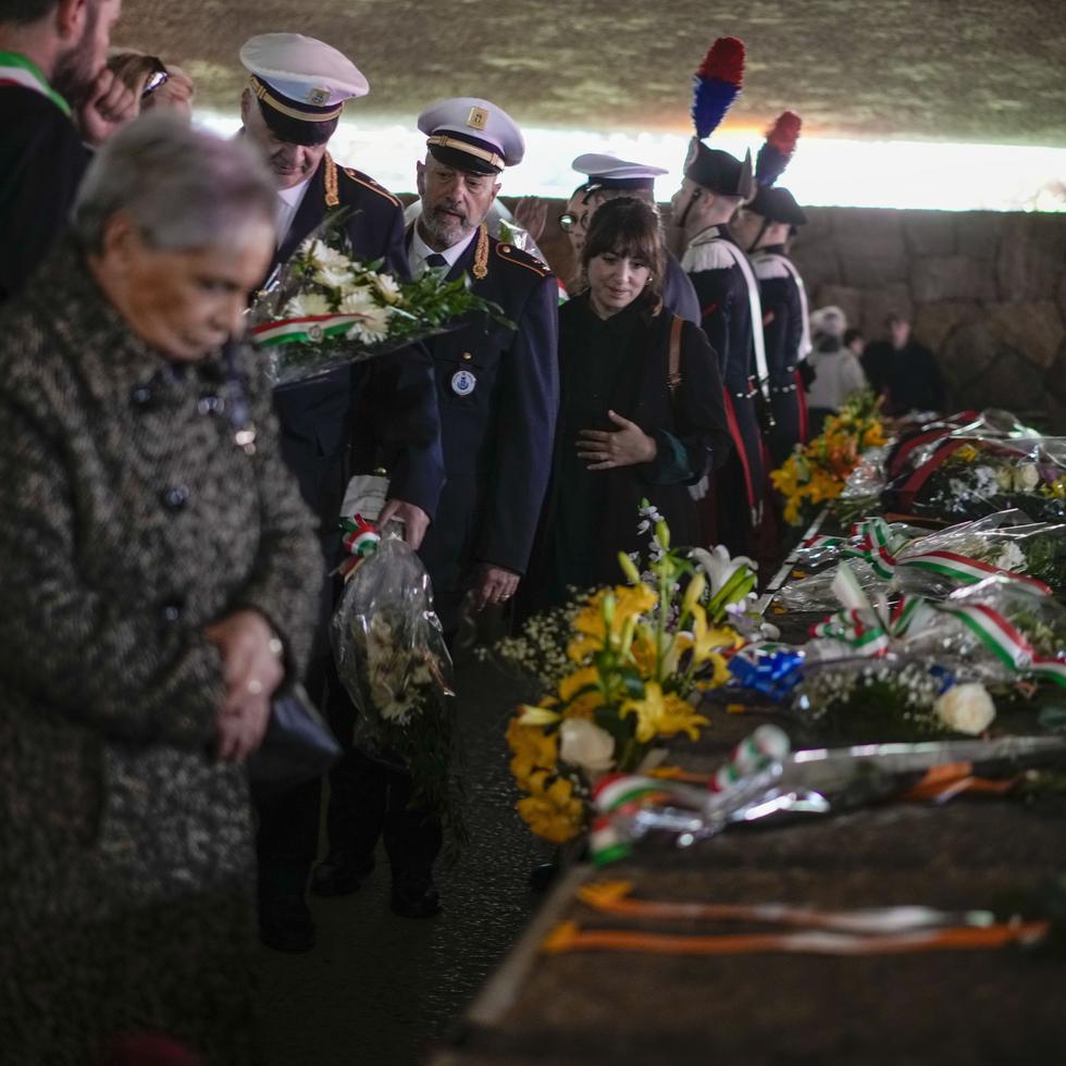 Varias personas depositan flores sobre las tumbas de las víctimas de la masacre de las Fosas Ardeatinas durante una ceremonia conmemorativa.