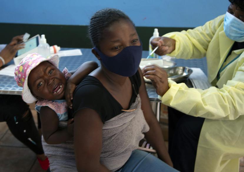 Un bebé llora mientras su madre recibe la vacuna de Pfizer contra COVID-19, en el municipio de Diepsloot, cerca de Johannesburgo.