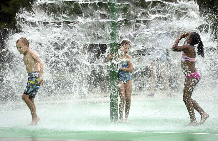 Niños juegan en agua para aminorar el calor que afecta a Estados Unidos. (AP)
