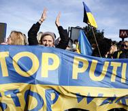 Manifestantes sostienen una pancarta con los colores nacionales de Ucrania y el mensaje "Detengan a Putin", cerca de la embajada rusa en Roma, el 24 de febrero de 2022.
