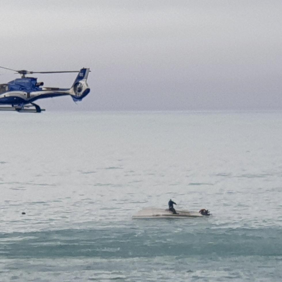Un helicóptero sobrevuela un barco volcado con un sobreviviente sentado sobre el casco, en la costa de Kaikoura, Nueva Zelanda, el 10 de septiembre de 2022.