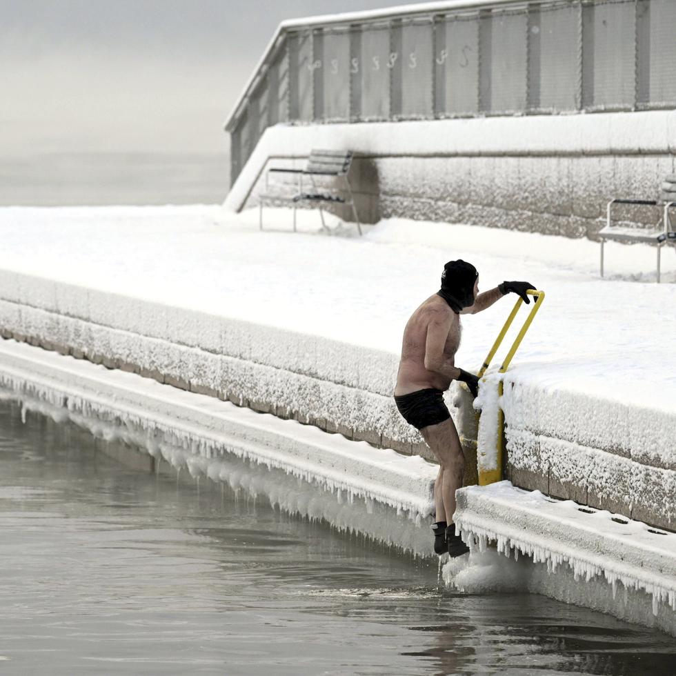 Un hombre sale del mar helado hasta el muelle, en el sur de Helsinki, Finlandia, el martes 2 de enero de 2024. Finlandia y Suecia registraron el martes récords de frío cuando las temperaturas cayeron a más de -40 grados.