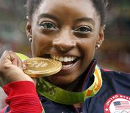 La gimnasta estadounidense Simone Biles muerde su medalla de oro tras ganar la medalla de oro en el concurso completo de los Juegos Olímpicos de Río de Janeiro 2016, el 11 de agosto de 2016.
